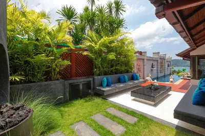 a garden with a blue couch and some plants at Stunning Sea & Sunset Views Villa over Patong Bay in Patong Beach