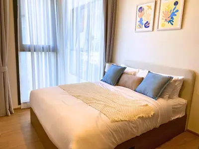 a bed with blue pillows in a room with a window at New 2 Br Apartment Cherng talay in Laguna Phuket