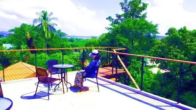 a person sitting on a balcony with a table and chairs at Jasmine Seaview 'B' Friendly Guest House in Ban Saiyuan (1)
