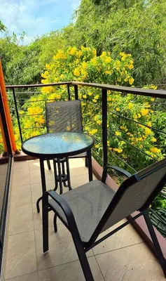 a table and a chair on a balcony with flowers at Jasmine Seaview 'C' Friendly Guest House in Ban Saiyuan (1)