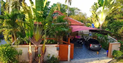 a car parked in front of a house with palm trees at Jasmine's Bungalow 3 bedroom 2 bathrooms Baby Cots in Ban Saiyuan (1)