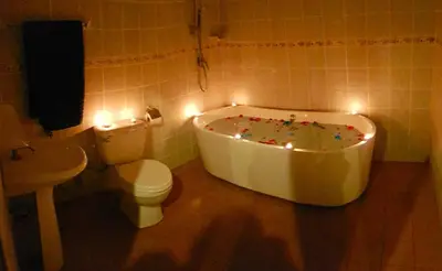 a bathroom with a tub and a toilet and lights at Jasmine's Bungalow 3 bedroom 2 bathrooms Baby Cots in Ban Saiyuan (1)