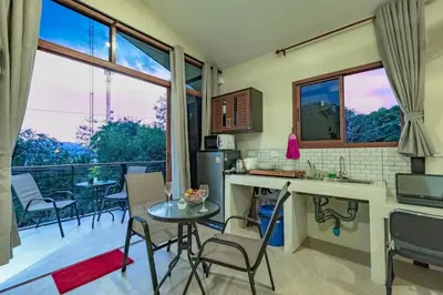 a kitchen with a table and chairs and a balcony at Jasmine Ocean View Penthouse in Ban Saiyuan (1)