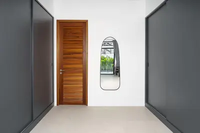 a hallway with a wooden door and a mirror at Alex Villa by G Estate Phuket in Ban Saiyuan (1)