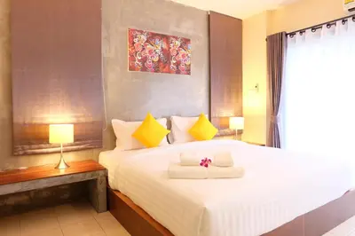 a bedroom with a large white bed with yellow pillows at The Meeting House Aonang - self service in Ao Nang Beach
