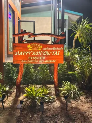 a sign in front of a building with plants at Happy Koh Yao Yai Bangkalo in Ban Tha Rua