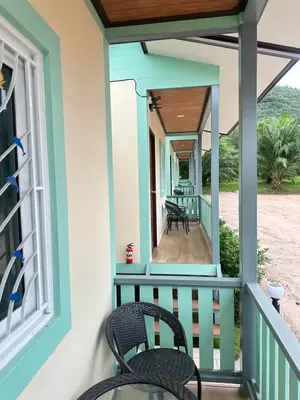 a porch of a house with two chairs and a window at Happy Koh Yao Yai Bangkalo in Ban Tha Rua