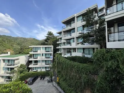 an apartment building with cars parked in a parking lot at A Taste of Utopia -Modern Phuket Retreat with Jacuzzi in Karon Beach
