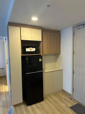 a small kitchen with a black refrigerator and cabinets at Laguna SkyPark in Laguna Phuket