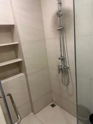 a shower with a glass door and shelves in a bathroom at Laguna SkyPark in Laguna Phuket