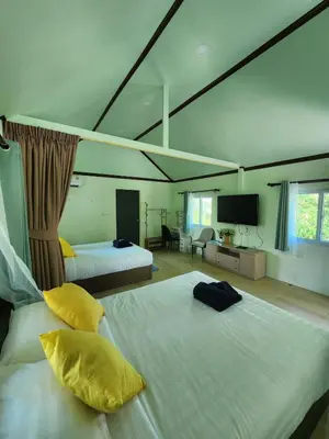 a hotel room with two beds and a television at Raya villa in Ban Muang Mai