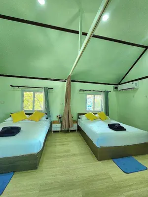 two beds in a room with two windows at Raya villa in Ban Muang Mai