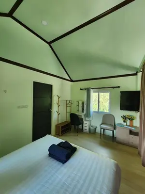 a bedroom with a bed and a desk and a tv at Raya villa in Ban Muang Mai