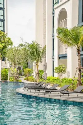 a swimming pool with chaise lounge chairs and palm trees at Title Halo Pinky Lime Naiyang Pool Gym Hammam in Ban Bo Han