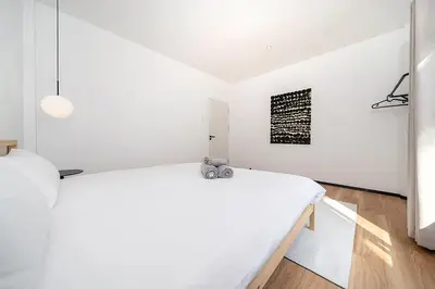a white bedroom with a bed and a painting on the wall at wolin patong greeen resort in Patong Beach