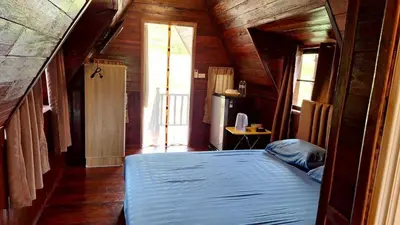 a bedroom with a bed in a wooden house at Meesaeng Homestay in Thalang