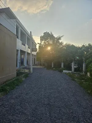 an empty road next to a building with the sun setting at The Hidden Place Bangtao in Ban Thalat Choeng Thale