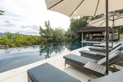 a swimming pool with lounge chairs and an umbrella at 6-Bedroom Private Luxury Pool Villa in Layan in Thalang