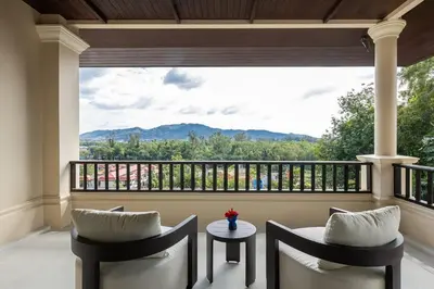 a balcony with two chairs and a table and a large window at 6-Bedroom Private Luxury Pool Villa in Layan in Thalang
