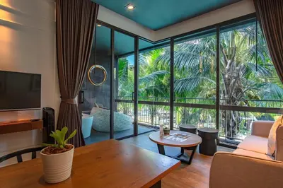 a living room with a couch and a large window at Saturdays Residence by Sure in Ban Saiyuan (1)