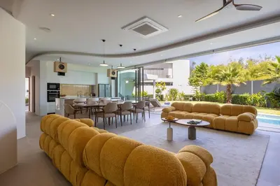 a living room with yellow couches and a dining room at Lux Nine Pasak by MonthstayZ Thailand in Ban Pak Lak
