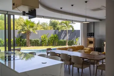 a living room with a table and chairs and a pool at Lux Nine Pasak by MonthstayZ Thailand in Ban Pak Lak
