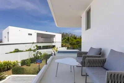 a balcony with a couch and chairs on a building at Lux Nine Pasak by MonthstayZ Thailand in Ban Pak Lak