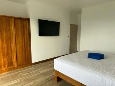 a bedroom with a bed and a television on the wall at Upstairs in Rawai Beach