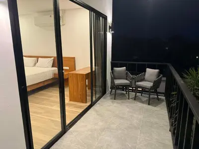 a balcony with a bed and two chairs and a table at Upstairs in Rawai Beach