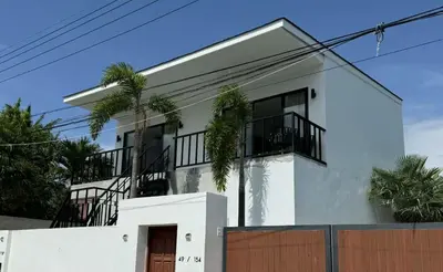 a white house with palm trees in front of it at Upstairs in Rawai Beach