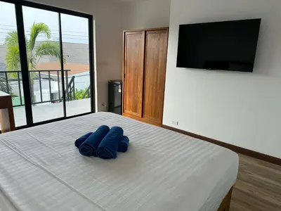 two blue slippers on a bed with a flat screen tv at Upstairs in Rawai Beach