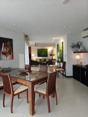 a living room with a wooden table and chairs at Dewa 1302 Poolside Resort Spacious 2 Bedroom in Phuket Town