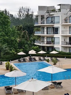a swimming pool with umbrellas and chairs and a building at Dewa 1302 Poolside Resort Spacious 2 Bedroom in Phuket Town