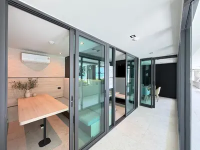 a room with glass walls and a wooden table at Gloria's Laguna Nest in Ban Thalat Choeng Thale