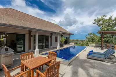 a patio with a table and chairs next to a swimming pool at Ao Yon- Contemporary 3-bedroom private pool villa in Ban Ao Makham