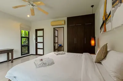 a bedroom with a white bed with a ceiling fan at Ao Yon- Contemporary 3-bedroom private pool villa in Ban Ao Makham