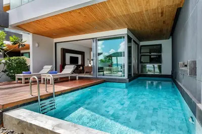 an indoor swimming pool with a patio and a house at Absolute Beachfront Villa 3-Bedroom in Rawai in Ban Saiyuan (1)