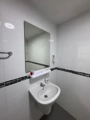 a white bathroom with a sink and a mirror at Pathaya in Ban Kata