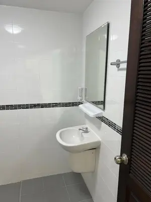 a white bathroom with a sink and a mirror at Pathaya in Ban Kata