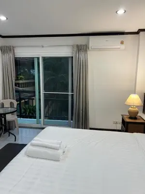 a bedroom with a large white bed and a window at Pathaya in Ban Kata