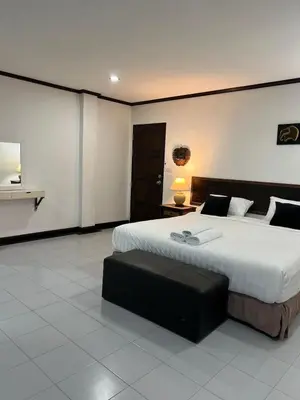 a large bedroom with a large bed and a bench at Pathaya in Ban Kata