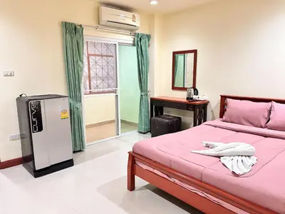 a bedroom with a pink bed and a refrigerator at Khan House Patong in Patong Beach