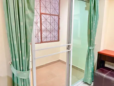 a glass door leading into a room with green curtains at Khan House Patong in Patong Beach