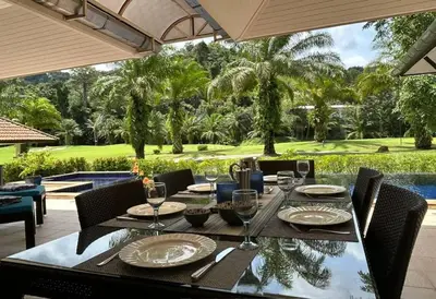 an outdoor dining table with a view of a golf course at Peaceful 2-Bedroom Villa on Loch Palm Golf Course in Ban Kathu