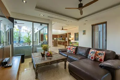 a living room with a leather couch and a table at Diamond Tree Escape Pool Villa in Bangtao in Ban Pak Lak