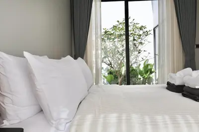 a white bed with white pillows and a window at Botanica - Bali Style Luxury 3 BR Private Pool Villa in Ban Pak Lak