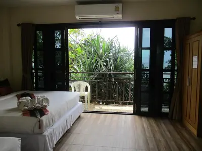a bedroom with two beds and a large sliding glass door at Phi Phi Green House & Sunsky Hostel in Phi Phi Don