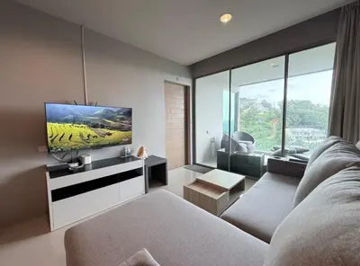 a living room with a couch and a flat screen tv at Veloche Karon by Investing In Phuket in Ban Karon