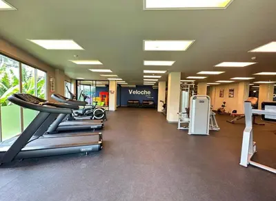a gym with treadmills and machines in a building at Veloche Karon by Investing In Phuket in Ban Karon
