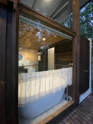 a window of a house with a bath tub at Kalm Cabin Phuket in Ban Phak Chit